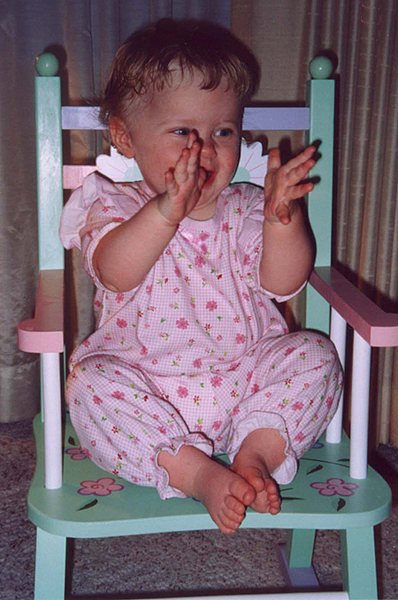 Baby girl feet on kiddie rocker.